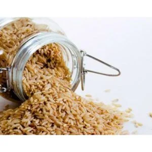 Brown rice spilling out of a glass jar.