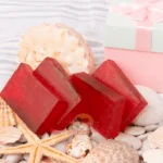 Red Wine Soap bars from DM Traders Organic Store arranged with seashells and a gift box.